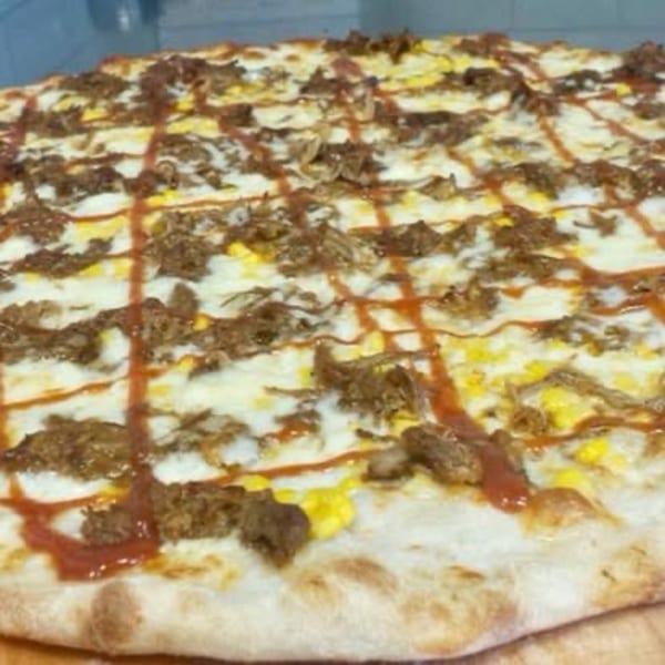A Pizza Village IV pizza with pulled pork, corn, and a BBQ sauce drizzle.