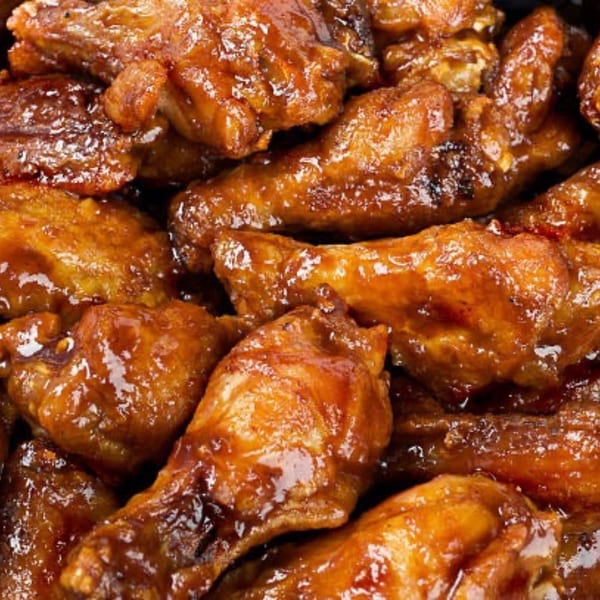 Close-up of a pile of glistening, saucy chicken wings from Pizza Village IV.