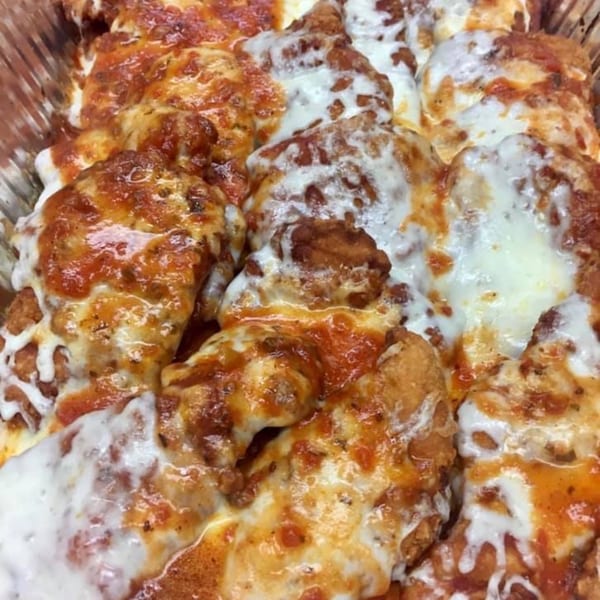 Close-up of baked chicken parmesan pieces covered in melted mozzarella cheese and red sauce.