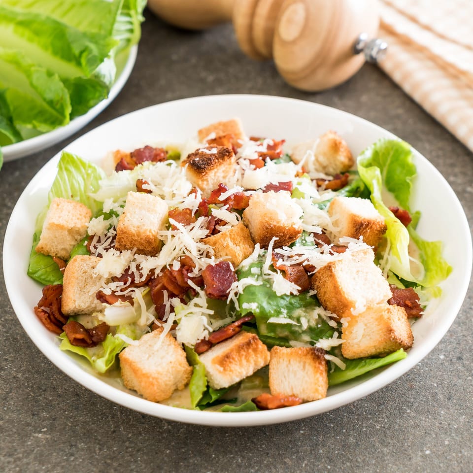 Caesar salad with crisp romaine lettuce, crunchy croutons, bacon bits, and shredded Parmesan cheese.