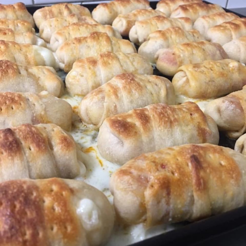 A tray of golden-brown baked pizza rolls, some with melted cheese oozing out.