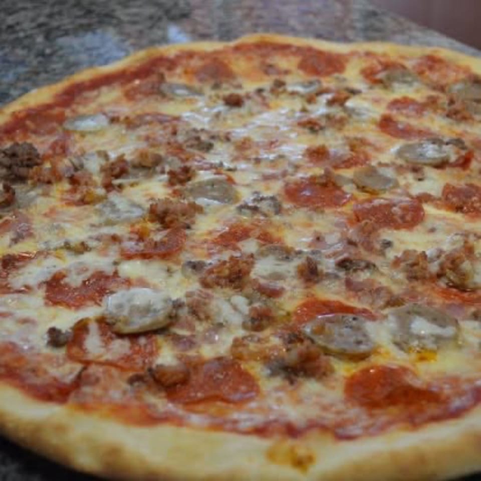 A whole Pizza Village IV pizza, topped with pepperoni, sausage, and melted cheese.